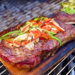 Gegrilde Ribeye steak met pepers en uien op cederhout