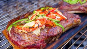 Gegrilde Ribeye steak met pepers en uien op cederhout